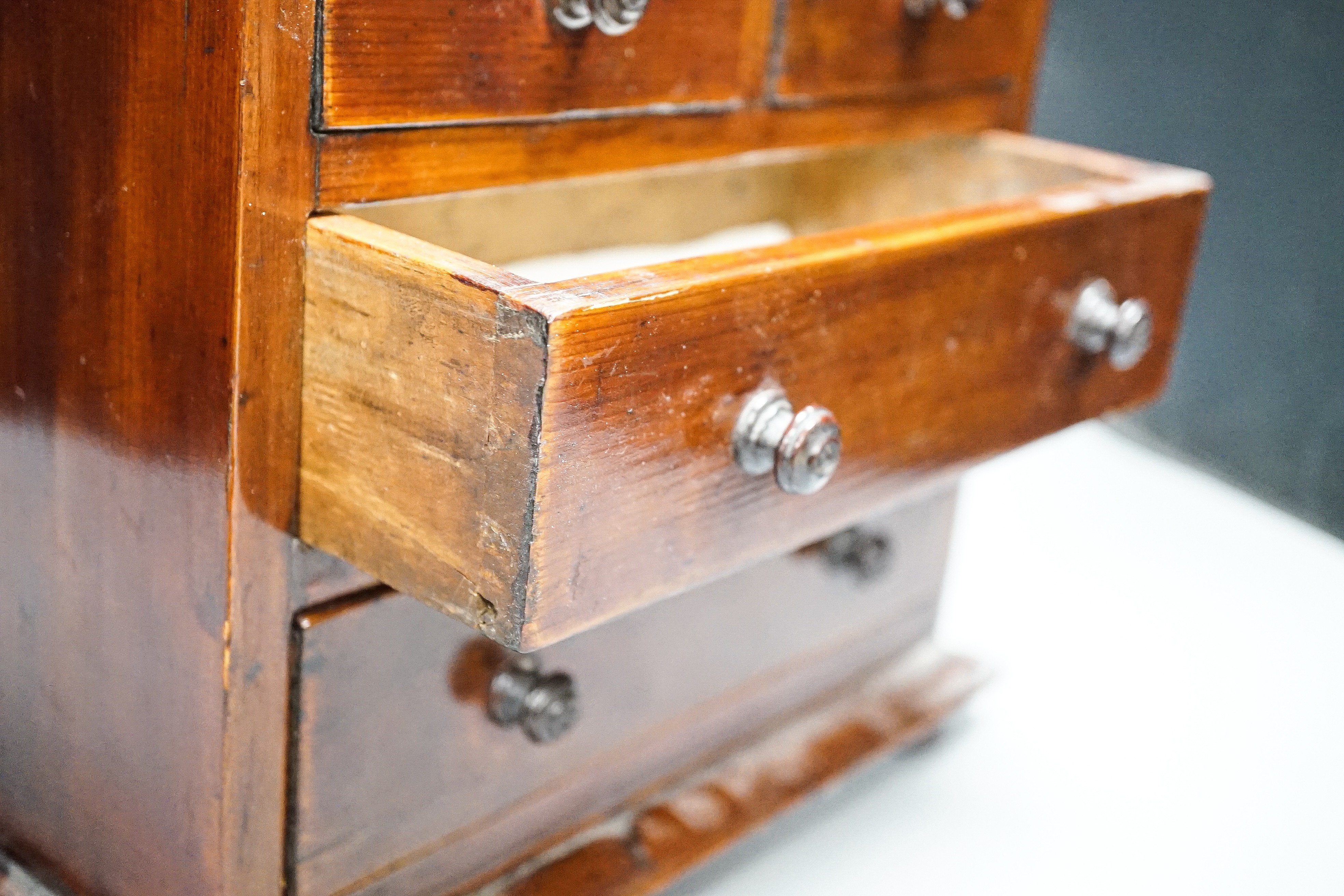 A Victorian stained pine miniature chest of drawers, 27 cms high.